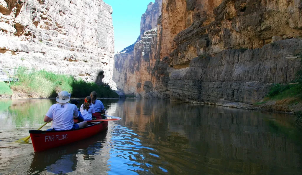 kayaks floating on a river through a canyon.