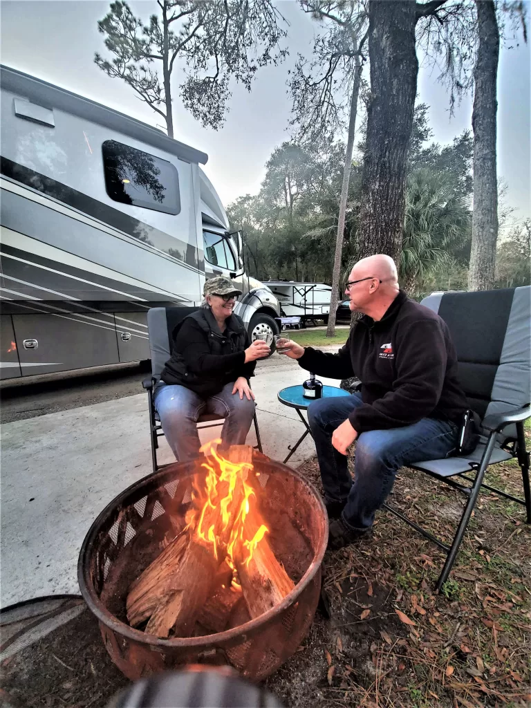 Full-Time Rv Living For Beginners: Start Here! 12 Happy camping couple relaxing and smiling by the fire pit.