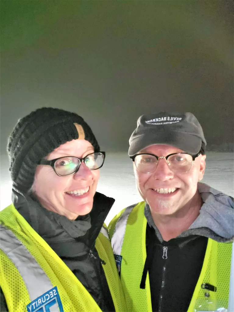 Gate Guarding: Work Camping Jobs For Full-Time Rvers 2024 17 Happy couple wearing safety vest and warm clothes.