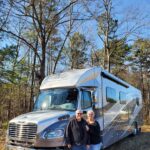 The stromads, an rving couple standing in front of their renegade verona super c rv.
