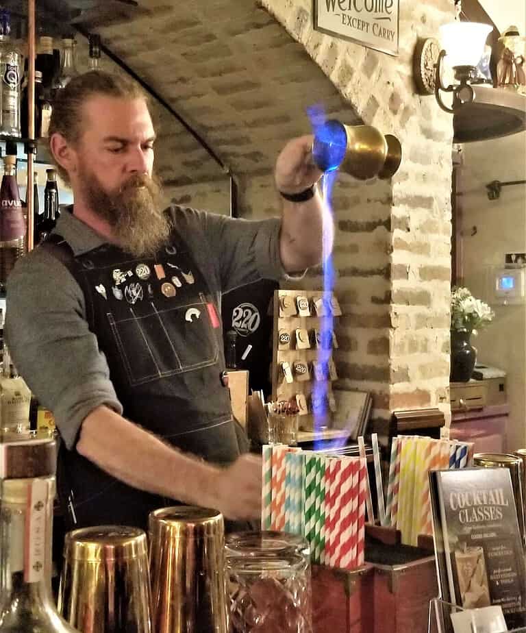 Mixologist pouring fire into a cocktail.