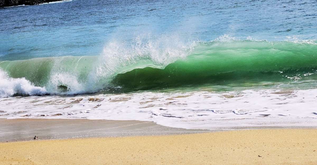 beaches_acadia_national_park nt green wave crashes onto the sandy shore at a beach in Acadia National Park.