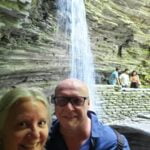 The Ultimate Guide To 30 Easy Finger Lakes Waterfalls With Map 2025 35 Maureen and robb, known as the stromads, smiling for a selfie in front of a picturesque cascading waterfall with layered rock formations. Other visitors can be seen enjoying the serene setting in the background