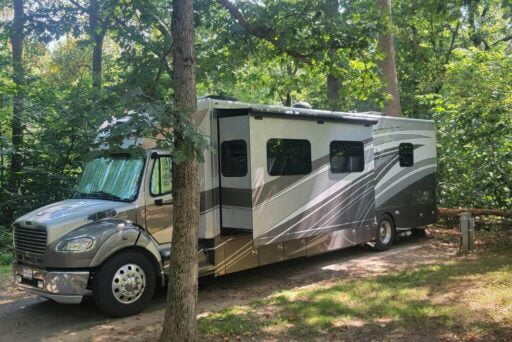 Rv Apps: Which Ones Do You Need? 14 A beautiful rv nestled in a serene, wooded campsite, illustrating the peace and tranquility that comes with rv living. It's a perfect representation of the rv lifestyle, where comfort meets adventure in beautiful natural settings.
