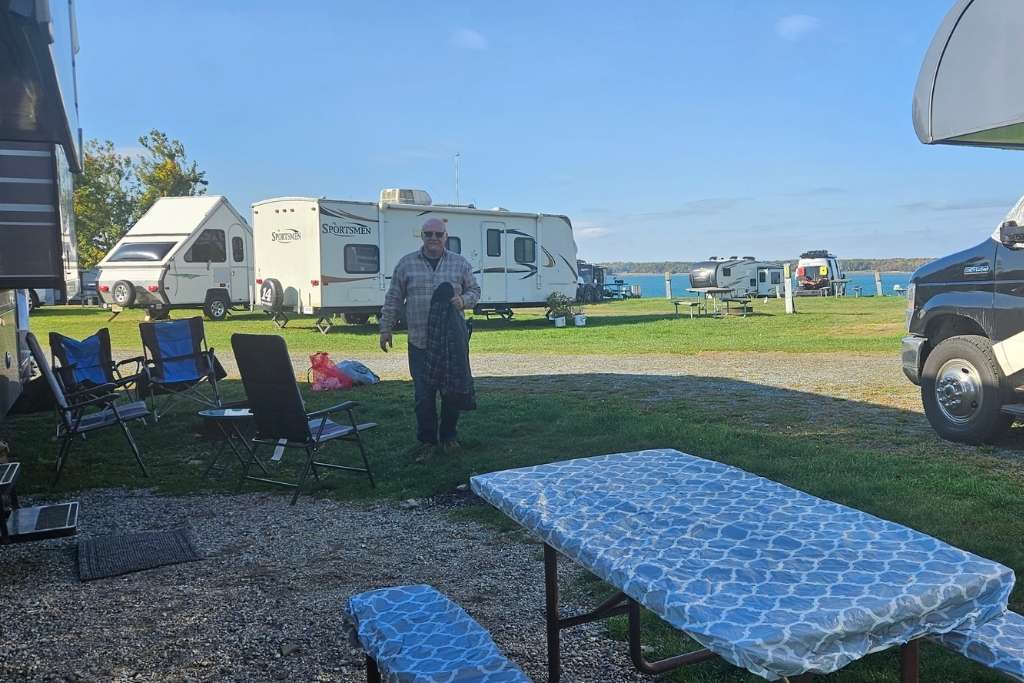 Rv-Friendly Campgrounds Acadia National Park: Best Big Rig Sites, 2026 216 Rv campground with picnic tables, folding chairs, and a man walking near parked campers by the water.