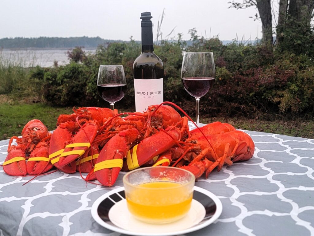Rv-Friendly Campgrounds Acadia National Park: Best Big Rig Sites, 2026 213 Freshly cooked lobsters with butter and red wine set on a table by the water, creating a scenic meal.