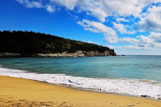 The Ultimate Acadia National Park Itinerary For 2025: Your Perfect 3-Day Plan 5 Sand beach in acadia national park, with golden sand, blue ocean waves, and rocky cliffs surrounded by lush green forest.