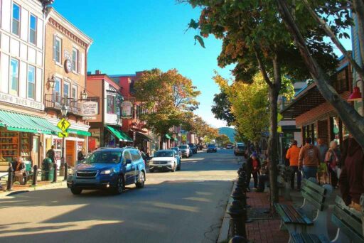 The Ultimate Acadia National Park Itinerary For 2025: Your Perfect 3-Day Plan 9 A bustling street in downtown bar harbor, maine, lined with shops, cafes, and autumn trees as people walk and cars pass by.