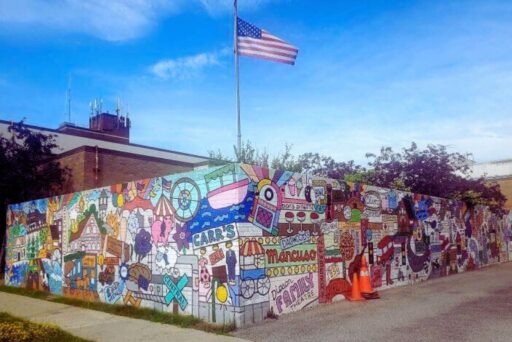 30 Best Things To Do In Batavia, Ny In 2025 8 Colorful mural in batavia, ny, featuring local landmarks, icons, and businesses under a waving american flag near the ramble festival site.