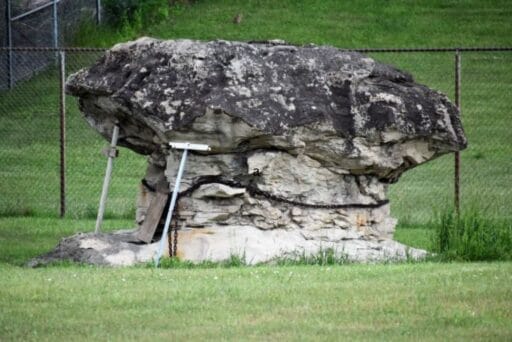 30 Best Things To Do In Batavia, Ny In 2025 5 Large, mushroom-shaped boulder known as devil’s rock in batavia, ny, supported by metal braces and surrounded by a fence.