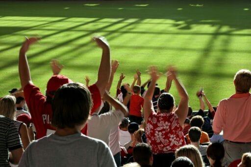 30 Best Things To Do In Batavia, Ny In 2025 14 Excited crowd cheering at a muckdogs baseball game in batavia, ny, with arms raised and bright green field in the background.