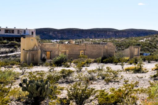 11 Fun Things To Do In Terlingua You Can’t Miss In 2025 5 Ruins of perry school in terlingua, texas, surrounded by desert plants and backed by cliffs and a restored building.