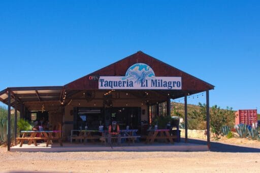 11 Fun Things To Do In Terlingua You Can’t Miss In 2025 18 Front view of taquería el milagro in terlingua, texas, with picnic tables, string lights, and a rustic desert backdrop.