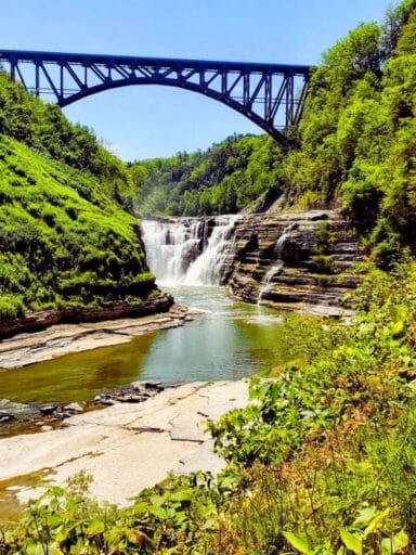 The Ultimate Guide To 30 Easy Finger Lakes Waterfalls With Map 2025 15 Upper falls at letchworth state park, flowing beneath a tall arched steel bridge surrounded by lush greenery.