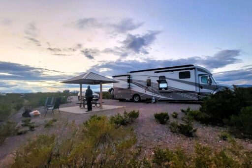 The Complete Guide To Full-Time Rv Living 10 Rv parked at desert campsite at sunset with person standing under a picnic shelter