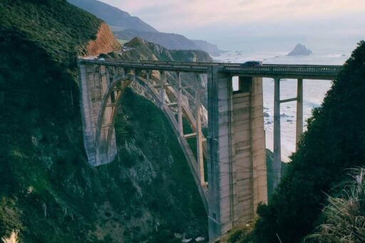 Bixby Creek Bridge: A Scenic Icon Among California’s Roadside Attractions  Cars drive over the iconic bixby creek bridge spanning a deep coastal canyon along california’s highway 1.