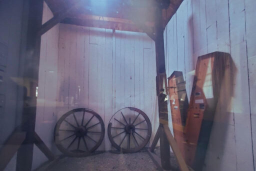 Historic Gibbet Exhibit At The Holland Land Office Museum A historic wooden gibbet and wagon wheels are displayed behind glass at the holland land office museum.