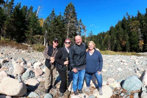 Friends hiking on a rocky trail through a forest on a sunny group trip