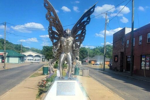 The Mothman Statue In Point Pleasant, West Virginia A towering chrome statue of the mothman with outstretched wings stands on a sidewalk in point pleasant, west virginia.