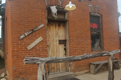 No Scum Allowed Saloon: A Legendary Cowboy Bar And Roadside Attraction In New Mexicoattraction Rustic brick saloon with a weathered wooden door and sign reading “no scum allowed” in a historic western town.