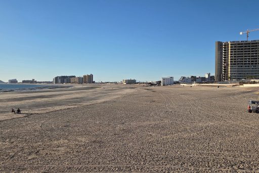Wide view of sandy beach in puerto peñasco with a long stretch of sand, resort buildings, and a few people walking along the shoreline. This open and peaceful beach scene shows the relaxed atmosphere that makes puerto peñasco worth visiting.