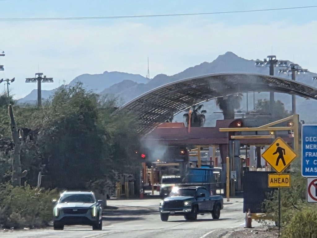 Lukeville border crossing into mexico with cars approaching inspection area desert landscape and sign reading