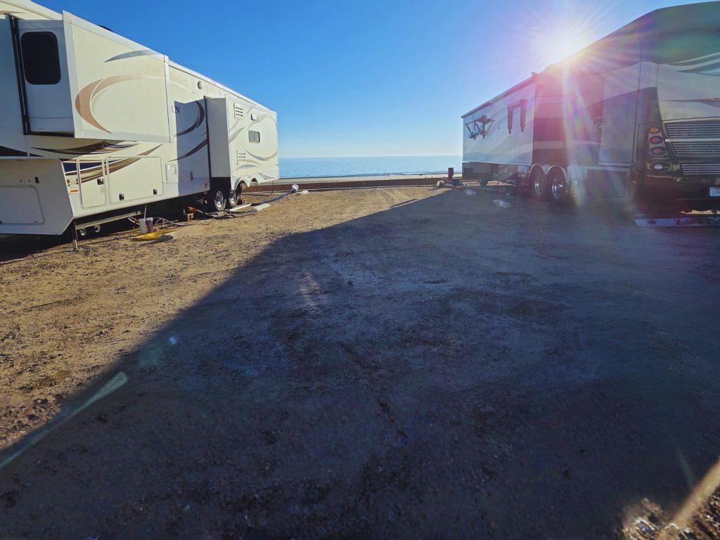 Rvs parked beachfront at playa bonita rv park in rocky point mexico with ocean view and bright sun over sandy campsite.