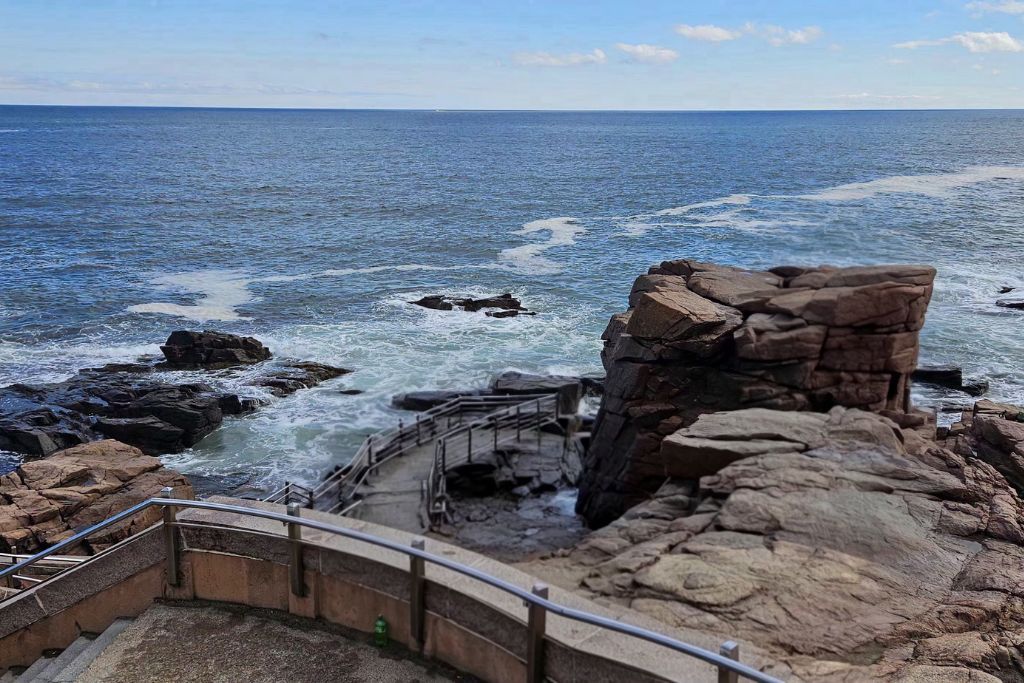 Thunder hole in acadia national park with waves crashing into rocky inlet below viewing platform and cliffs