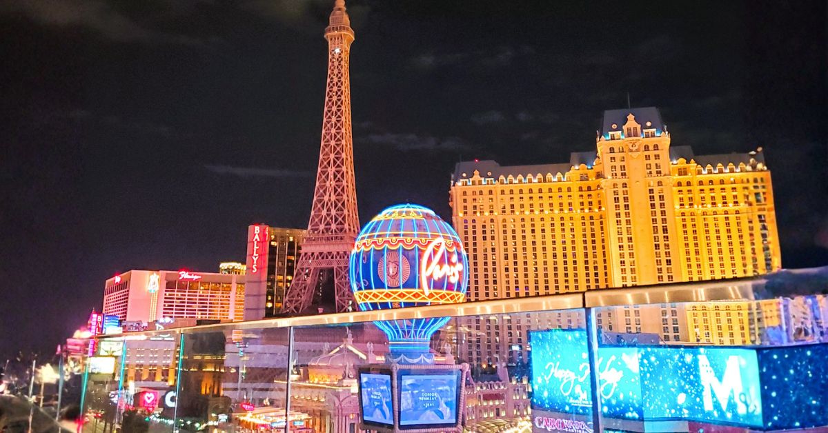 Las Vegas Strip at night with Paris Eiffel Tower and glowing balloon sign. A vibrant scene for Where to Stay in Las Vegas.