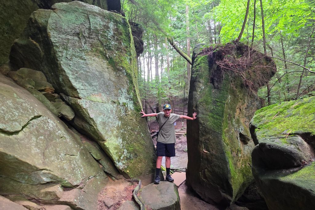 Missouri Road Trip Itinerary: Branson, The Ozarks &Amp; Beyond 3 Mason standing between giant mossy boulders on the cedar falls trail at hocking hills state park.