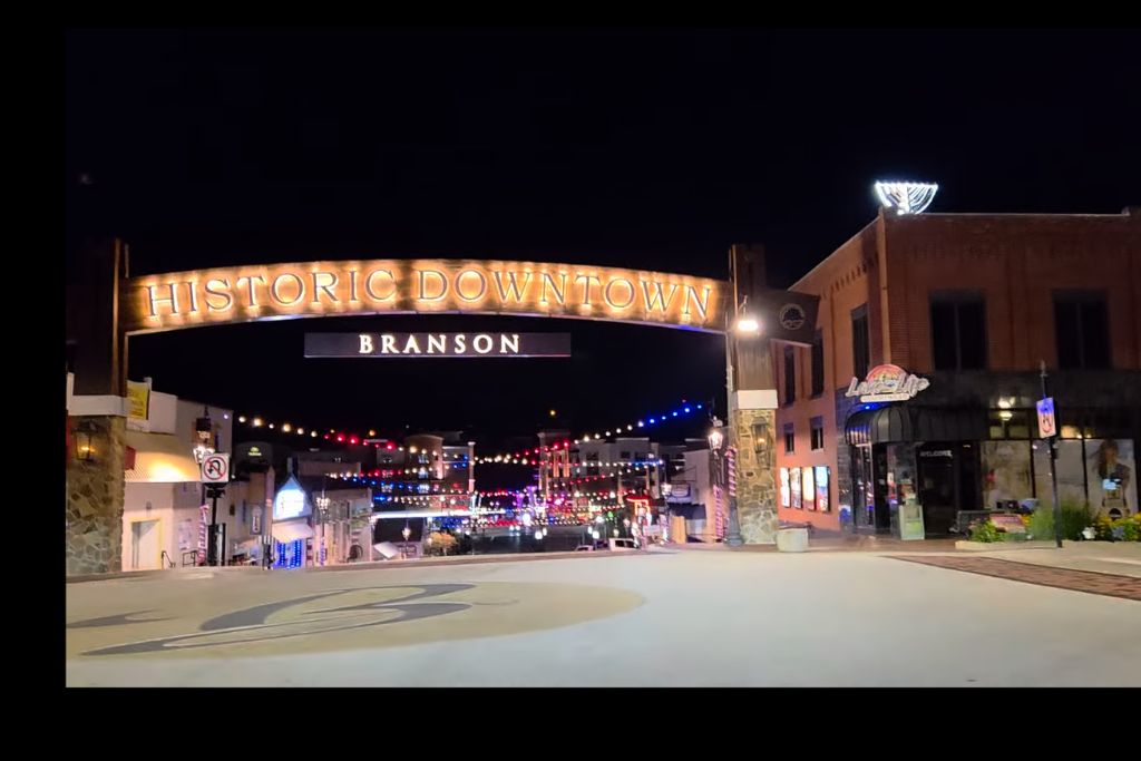 Missouri Road Trip Itinerary: Branson, The Ozarks &Amp; Beyond 20 Historic downtown branson at night with colorful string lights hanging above the street, local shops, and parked cars creating a lively evening atmosphere.