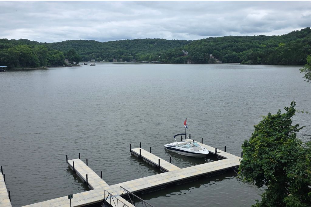 Missouri Road Trip Itinerary: Branson, The Ozarks &Amp; Beyond 27 A small boat sits at a quiet dock on the lake of the ozarks with calm water and forested hills beneath cloudy skies. Maureen would spend more time researching and exploring the area on a future missouri road trip.