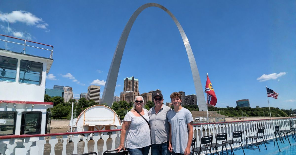 Family posing on a Mississippi River cruise with the Gateway Arch during a St. Louis Road Trip.