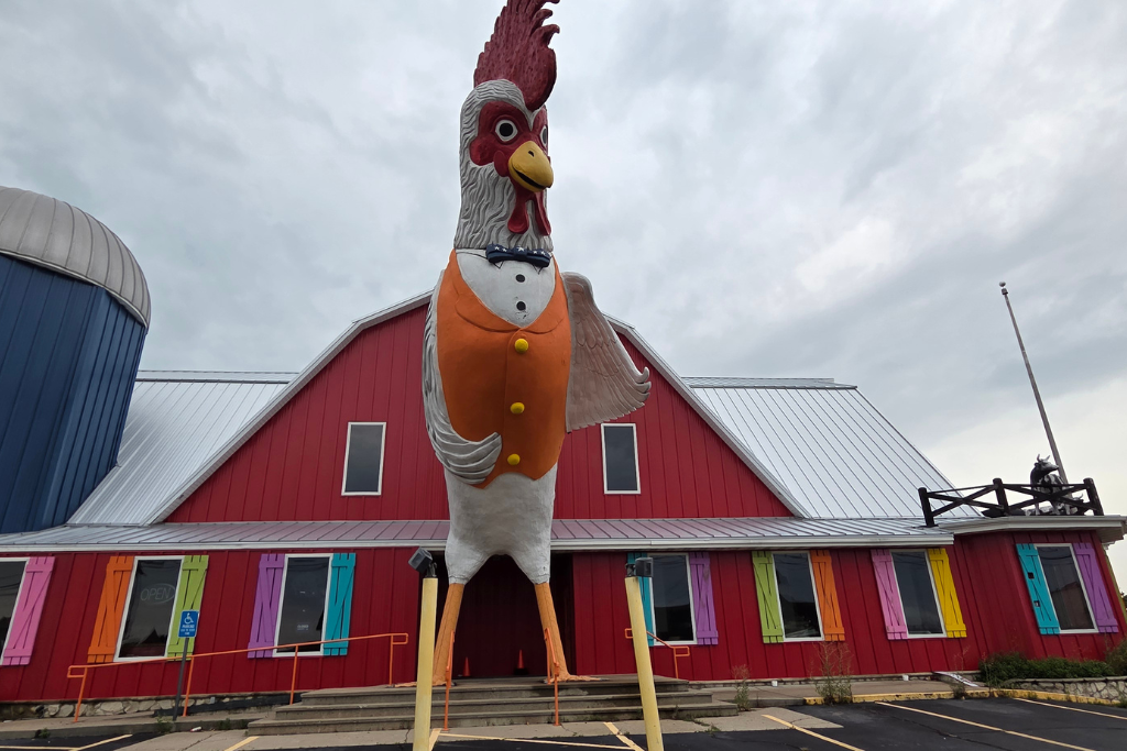 Is Branson Worth Visiting? Our Thoughts After Three Days 11 Giant rooster statue outside a colorful roadside attraction in branson with a bright red barn-style building and rainbow window shutters. While branson has plenty to offer, not every attraction was a hit for our family.