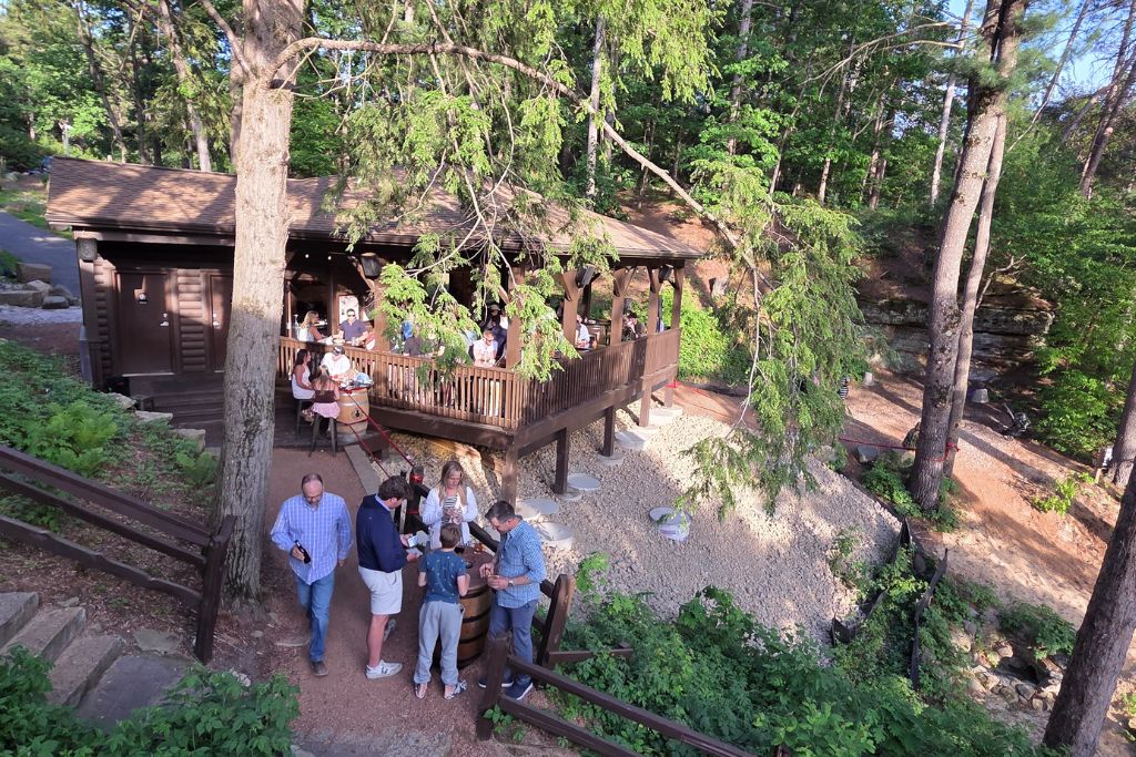 Wisconsin Dells For Adults: Beyond The Waterparks 12 Guests gather around a rustic outdoor bar and patio tucked among tall trees at ishnala supper club.