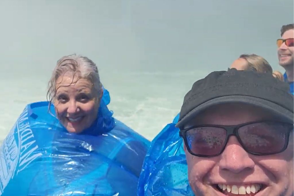 Is Niagara Falls Worth Visiting? What We Think After Several Visits 10 Robb and maureen smile at the camera in blue ponchos with wet hair and water covering their faces after getting soaked on maid of the mist. Their expressions capture the fun of experiencing niagara falls from the water.