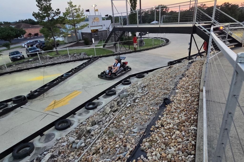 Is Branson Worth Visiting? Our Thoughts After Three Days 2 Mason drives a go kart around an outdoor track in branson at sunset, with bridges, curves, and the surrounding attractions visible. Racing go karts was one of the fun family activities that helped answer the question, is branson worth visiting.