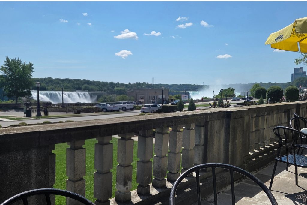 Is Niagara Falls Worth Visiting? What We Think After Several Visits 2 Outdoor patio tables at secret garden restaurant overlook american falls and the mist from horseshoe falls across the niagara river. The sunny canadian side location provided a scenic lunch stop during a day at niagara falls.