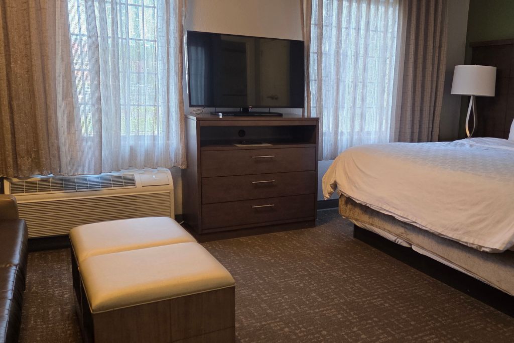 Wisconsin Dells For Adults: Beyond The Waterparks 17 Guest room at staybridge suites with a large bed. A television and dresser sit between tall windows with sheer curtains.