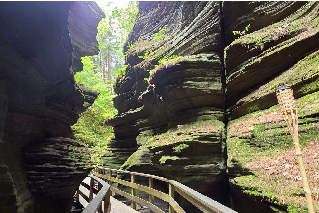 Wisconsin Dells For Adults: Beyond The Waterparks 5 Narrow witches gulch boardwalk passes beneath massive layered sandstone walls covered with green moss.