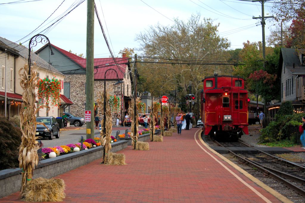 New Hope And Lambertville Fall Day Trip Guide 1 Red railroad caboose beside a brick platform decorated with colorful mums, pumpkins, and cornstalks in new hope, pa.