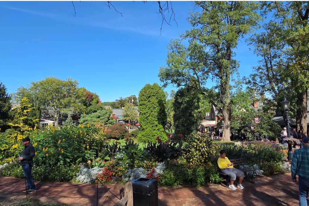 New Hope And Lambertville Fall Day Trip Guide 6 Colorful gardens, brick walkways, benches, and visitors enjoying peddler's village in lahaska, pennsylvania.