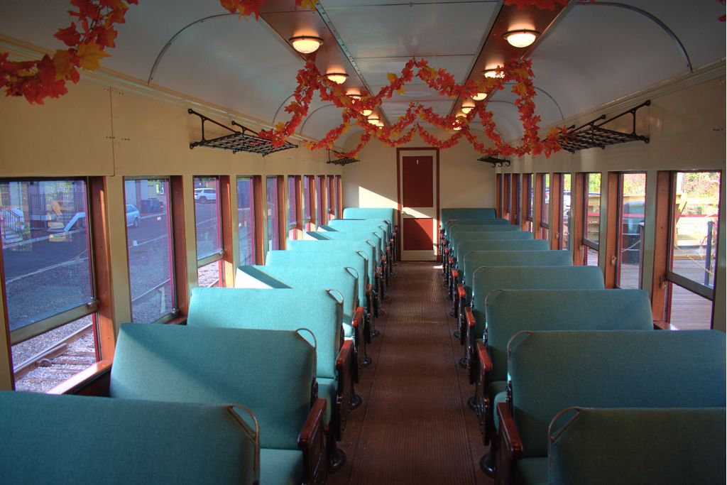 New Hope And Lambertville Fall Day Trip Guide 10 Rows of teal upholstered seats fill a vintage new hope railroad coach decorated with orange and red autumn leaf garlands.
