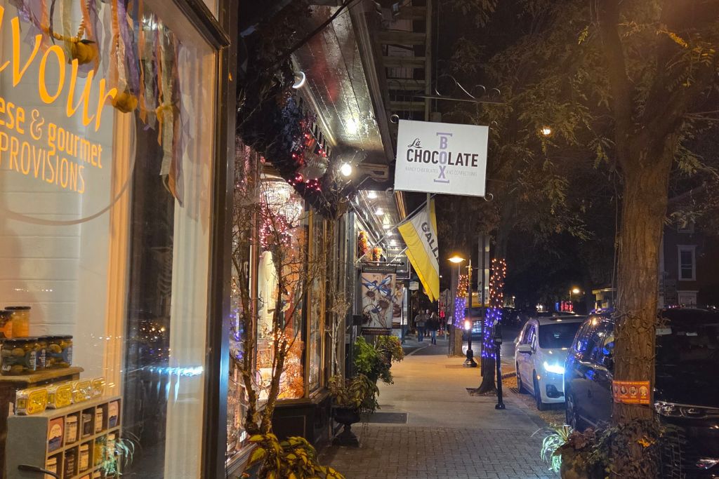 New Hope And Lambertville Fall Day Trip Guide 13 Lambertville storefronts glow at night along union street with seasonal lights, parked cars and shoppers on the sidewalk.