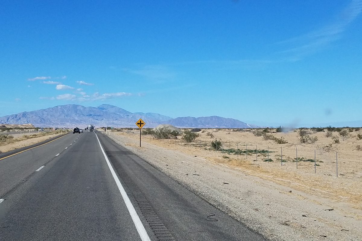 Open desert highway heading toward distant mountains