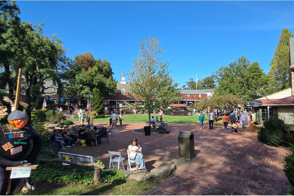 Peddler'S Village Fall Scarecrows And Shopping In Lahaska Pa Visitors stroll the brick pathways of peddlers village on a sunny fall day with a halloween scarecrow outside the shops.