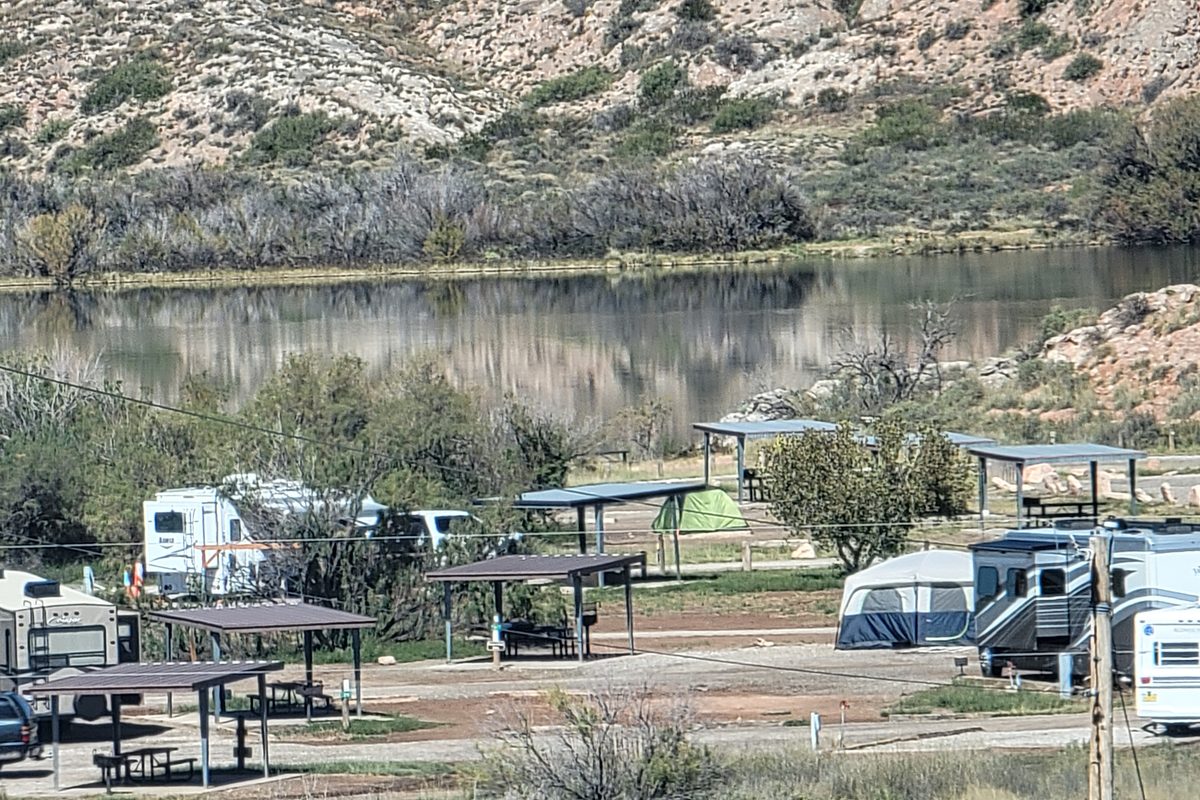 Rv campground beside a lake with canyon walls behind