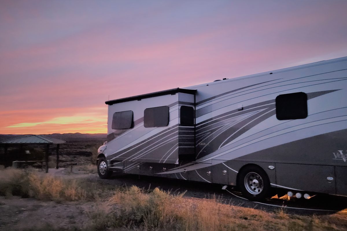 Rv parked at sunset with a pink and orange sky