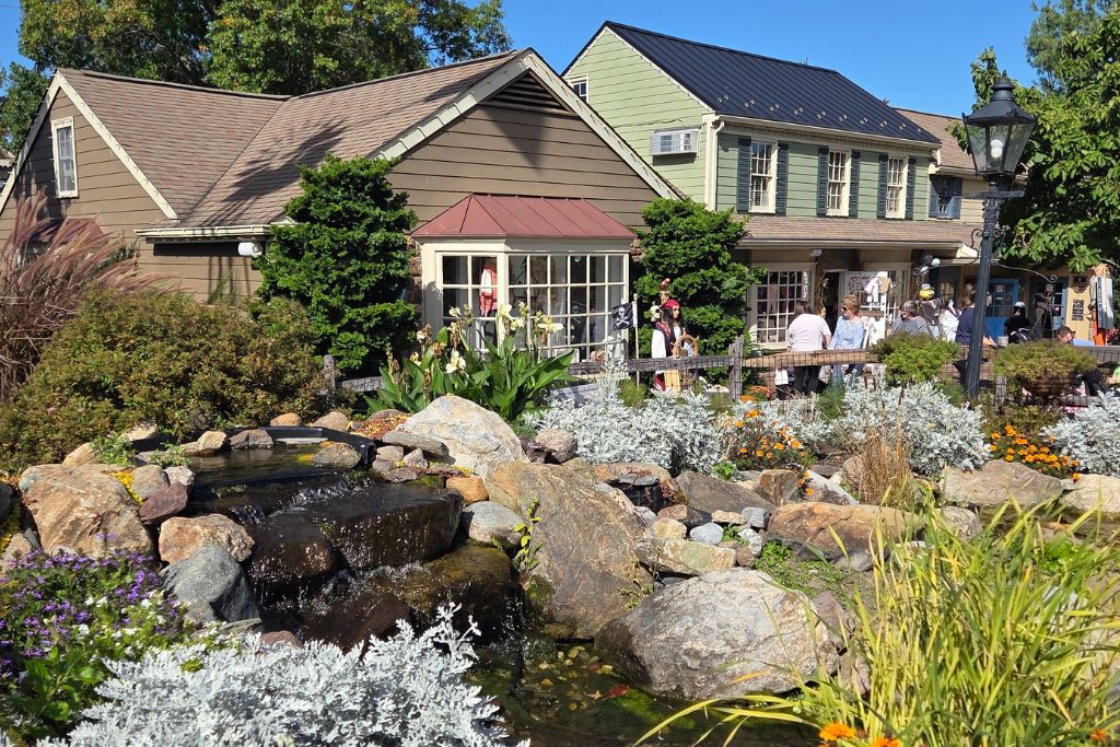 New Hope And Lambertville Fall Day Trip Guide 2 Landscaped waterfall, colorful gardens, historic shops, and visitors at peddler's village in lahaska, pennsylvania.